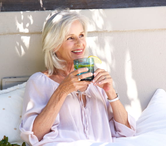 Older woman drinking tea outdoors.